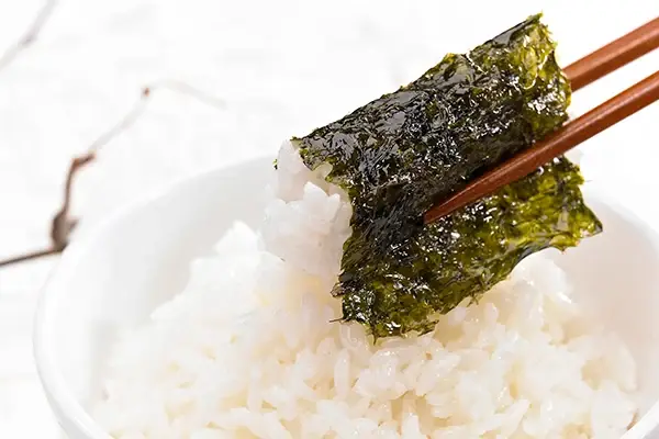 Nori sheet wrapped around rice, held with chopsticks